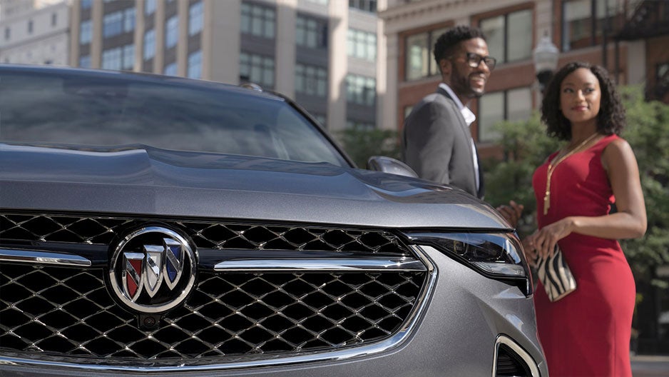 Man and woman standing next to Buick car